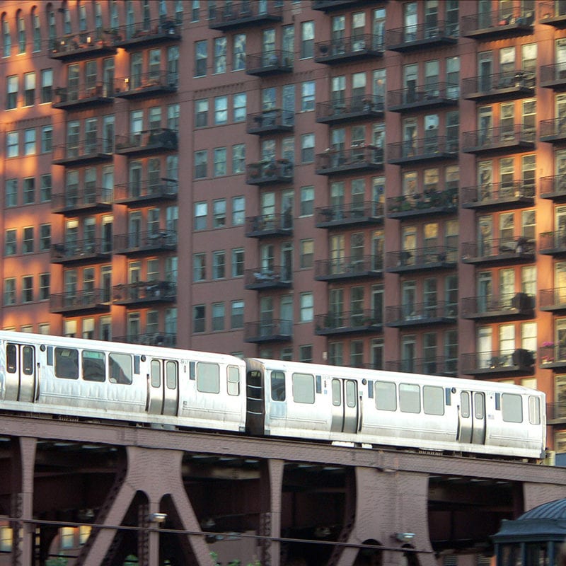 El train goes past a large apartment building in Chicago