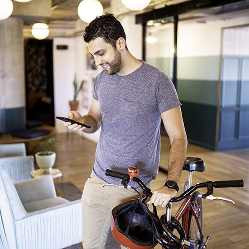 Young Businessman Entering Using Mobile With Bicycle At Modern Office