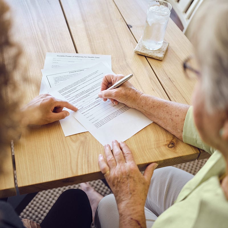 Older woman signs paperwork
