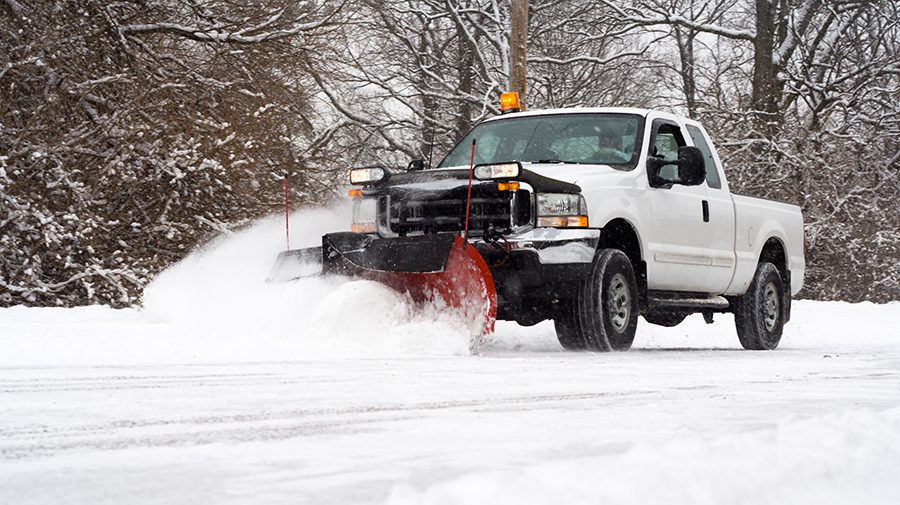 Man in pickup truck plowing road during snow storm