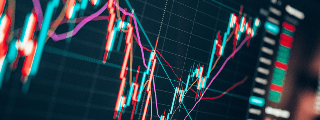 A close-up view of a digital financial chart displays multiple colored lines and candlesticks indicating market trends and price changes.
