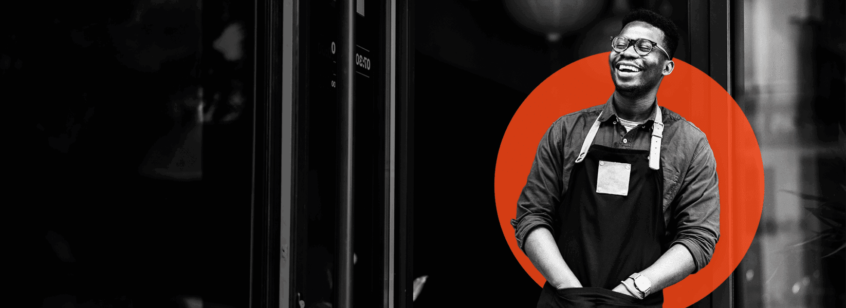 A person wearing glasses and an apron stands in front of a building, smiling, with a red circle graphic behind them.