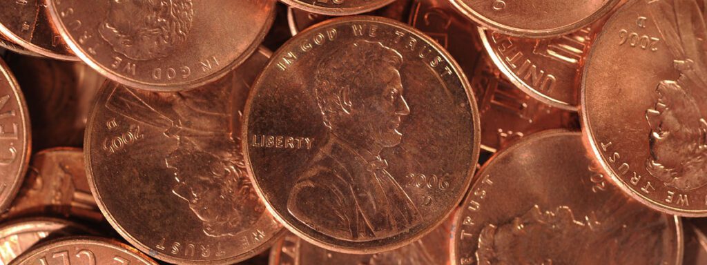 Close-up of a pile of U.S. one-cent coins (pennies), with the heads side featuring Abraham Lincoln prominently visible.