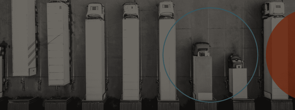 Aerial view of several semi-trucks and trailers parked in parallel rows at a lot, with two vehicles inside a highlighted blue circle.