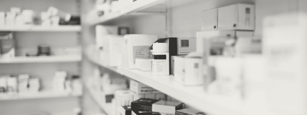 Shelves filled with various medicine boxes and bottles in a pharmacy or medical storage area, arranged in rows.