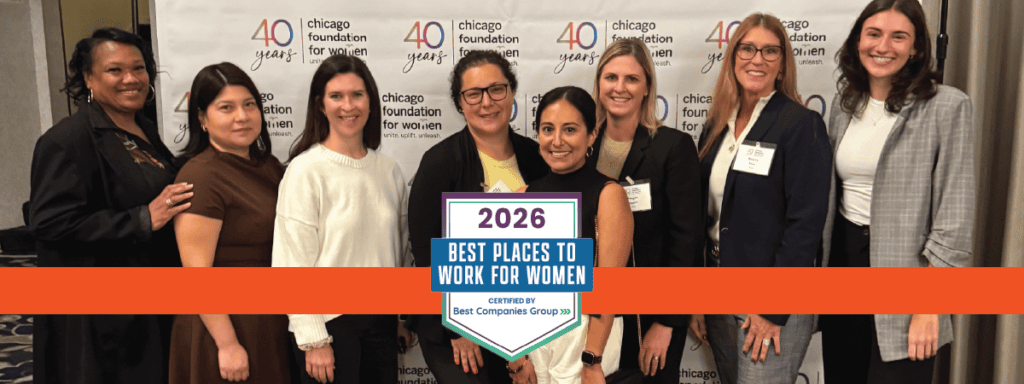 A group of nine women stand together, smiling, in front of a Chicago Foundation for Women banner with a “2026 Best Places to Work for Women” sign in front of them.