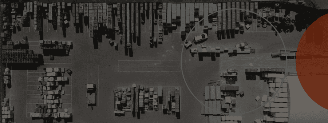 Aerial view of an industrial storage yard with organized rows of materials, several parked vehicles, and a large blue circle overlay on the right.